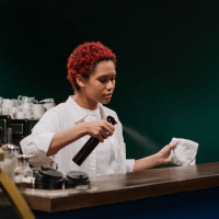 Woman cleans bar top with spray and cloth Woman cleans bar top with spray and cloth
