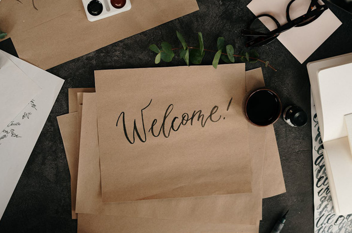 Papers on a busy desk with the word Welcome written on it Papers on a busy desk with the word Welcome written on it