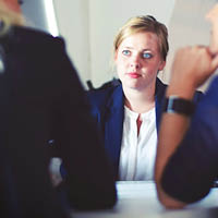 Woman speaking to 2 people at a table Woman speaking to 2 people at a table