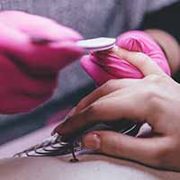 Nail technician wearing PPE buffing the nails of a client Nail technician wearing PPE buffing the nails of a client