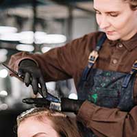 Hairdresser applying dye to a client's hair Hairdresser applying dye to a client's hair